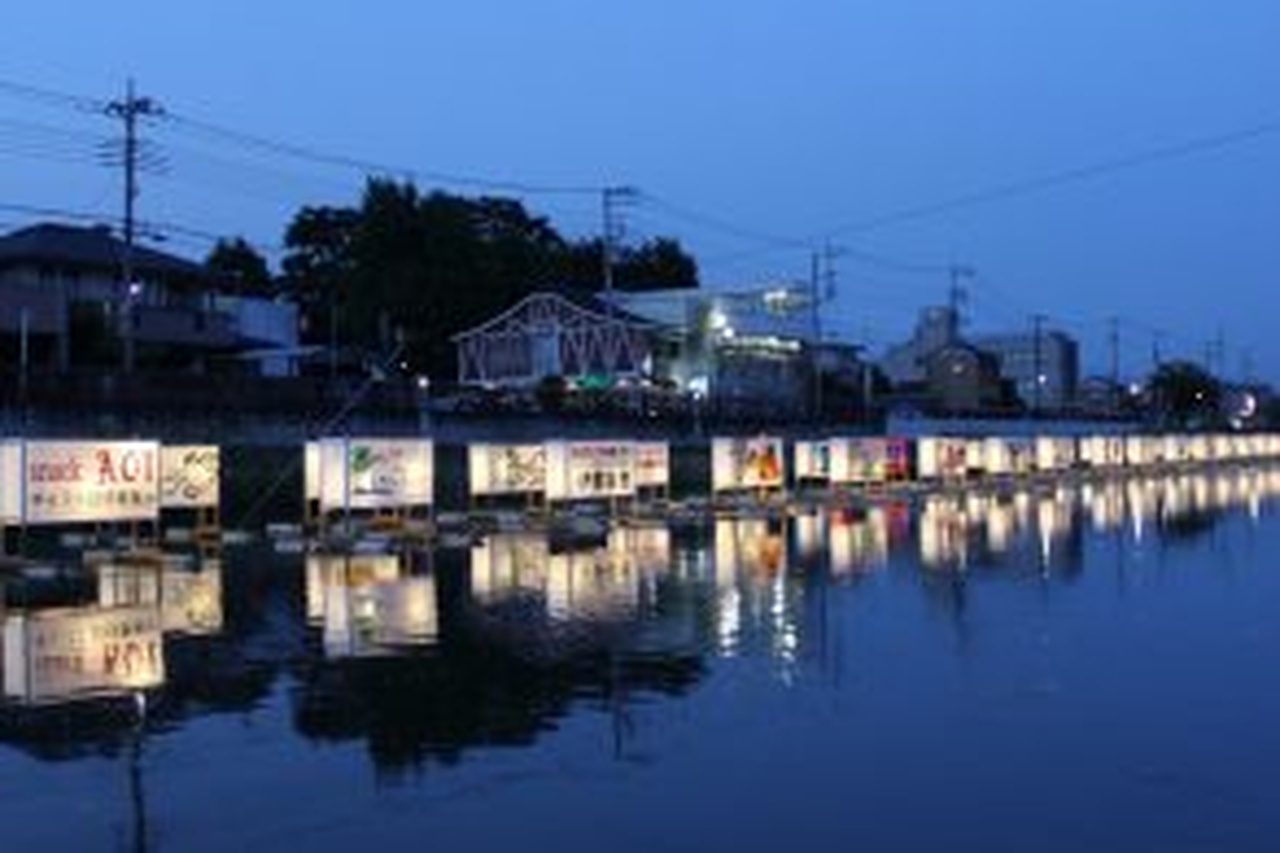 夜の古利根川に漂う灯籠が静かに輝く流灯の光景