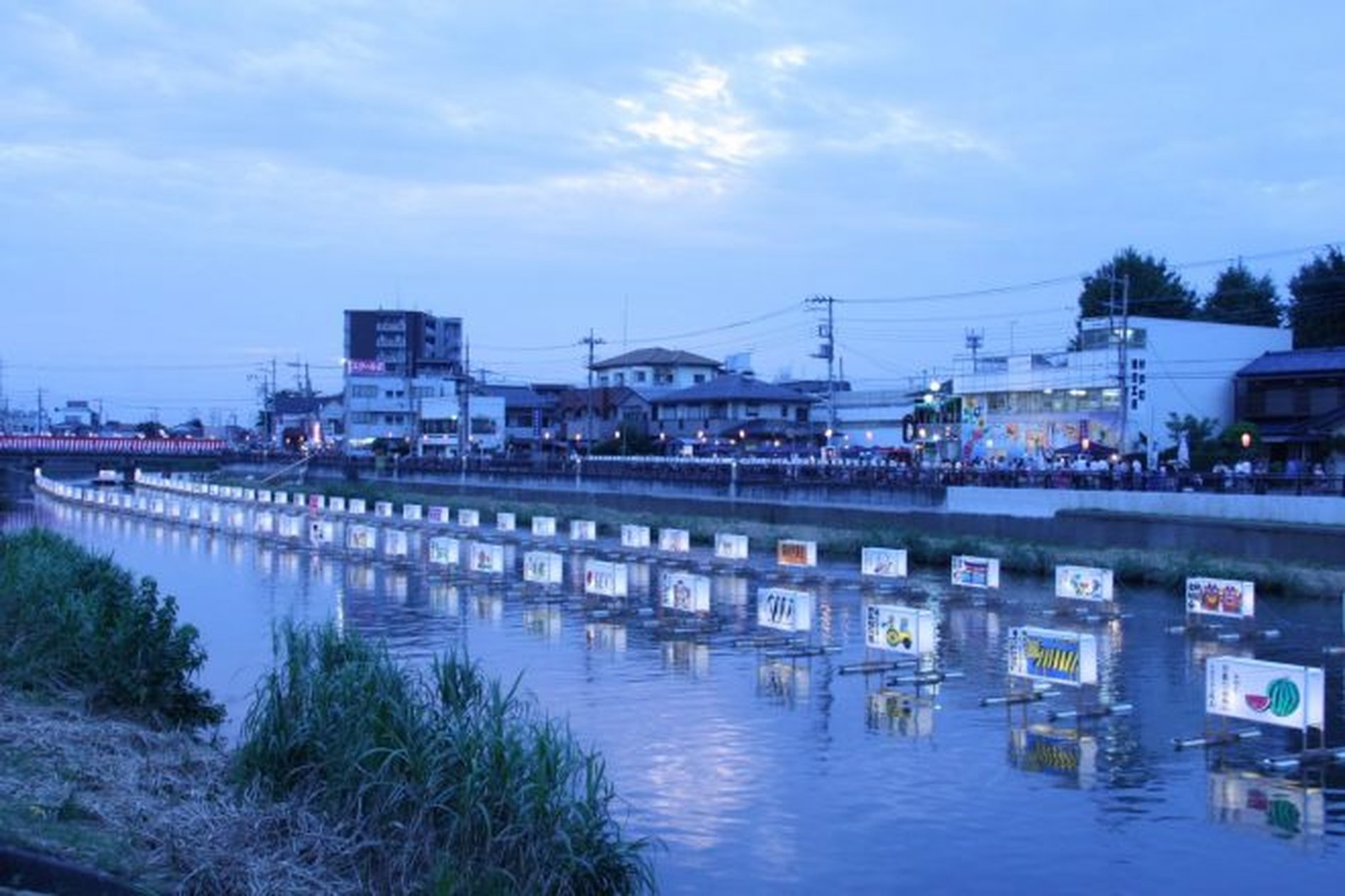 青く染まる古利根川に灯籠が整然と浮かぶ光景