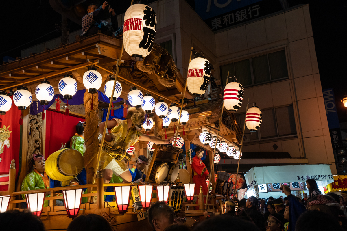 夜の飯能まつりで灯りに彩られた山車と演者の舞の風景
