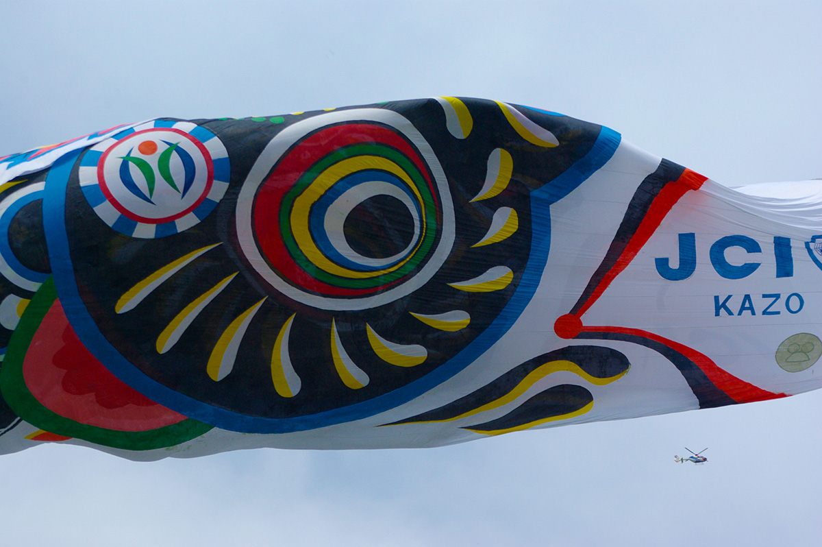 広場でスタッフがジャンボこいのぼりの布を広げ、準備作業を進めている様子