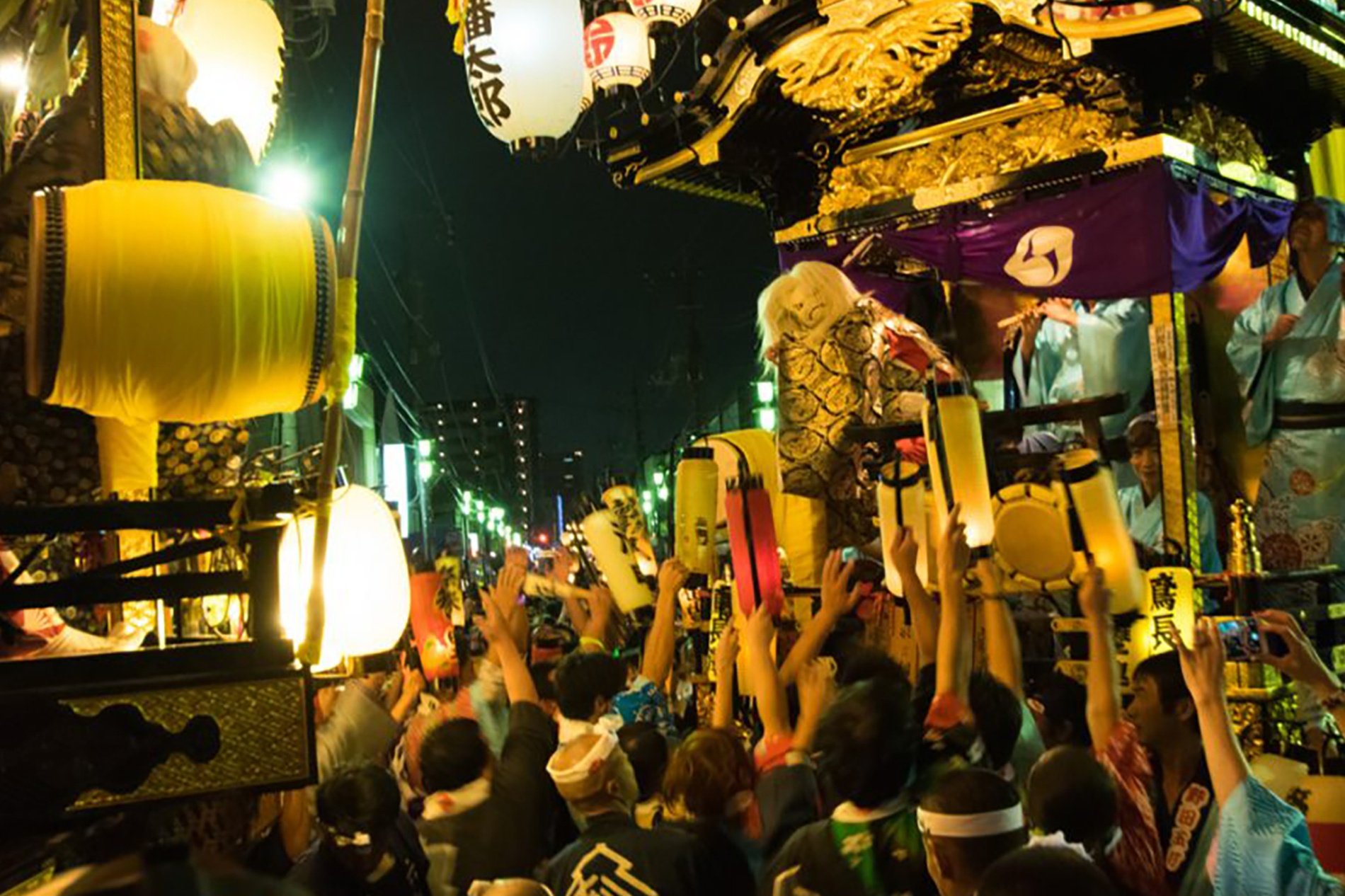 夜の川越まつりで、提灯を掲げる人々と豪華な山車