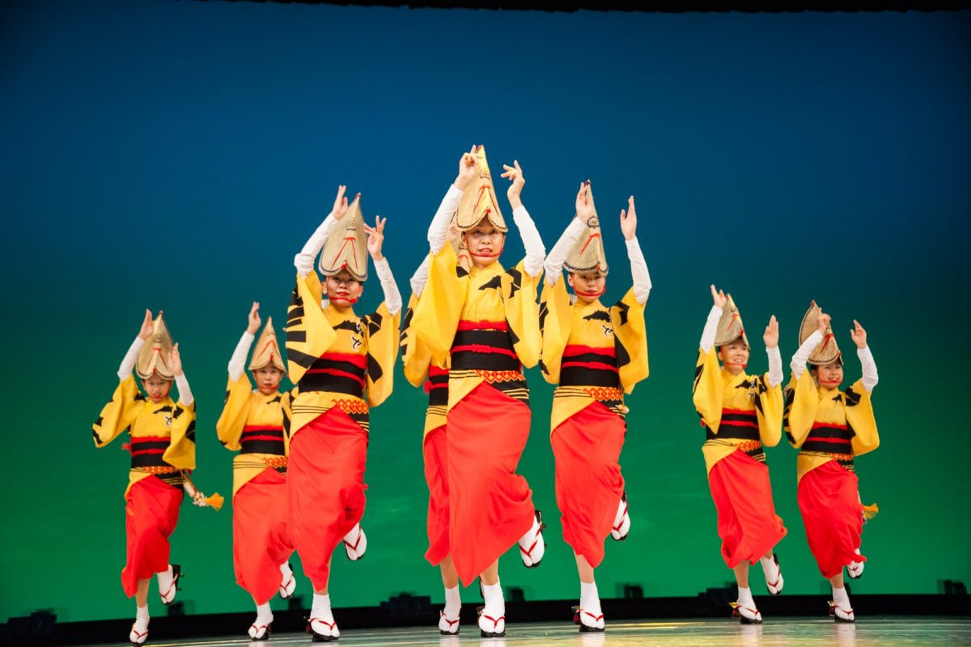 南越谷阿波踊りで、黄色い法被と赤い袴を着た子ども連が舞台上で躍動的に踊る姿