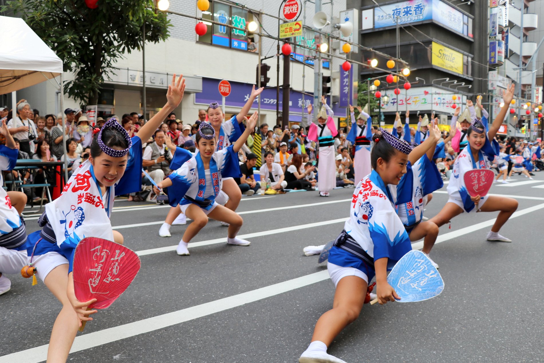 南越谷阿波踊りのパレードで、青と白の衣装の子ども達が道路で大きくポーズを決めている