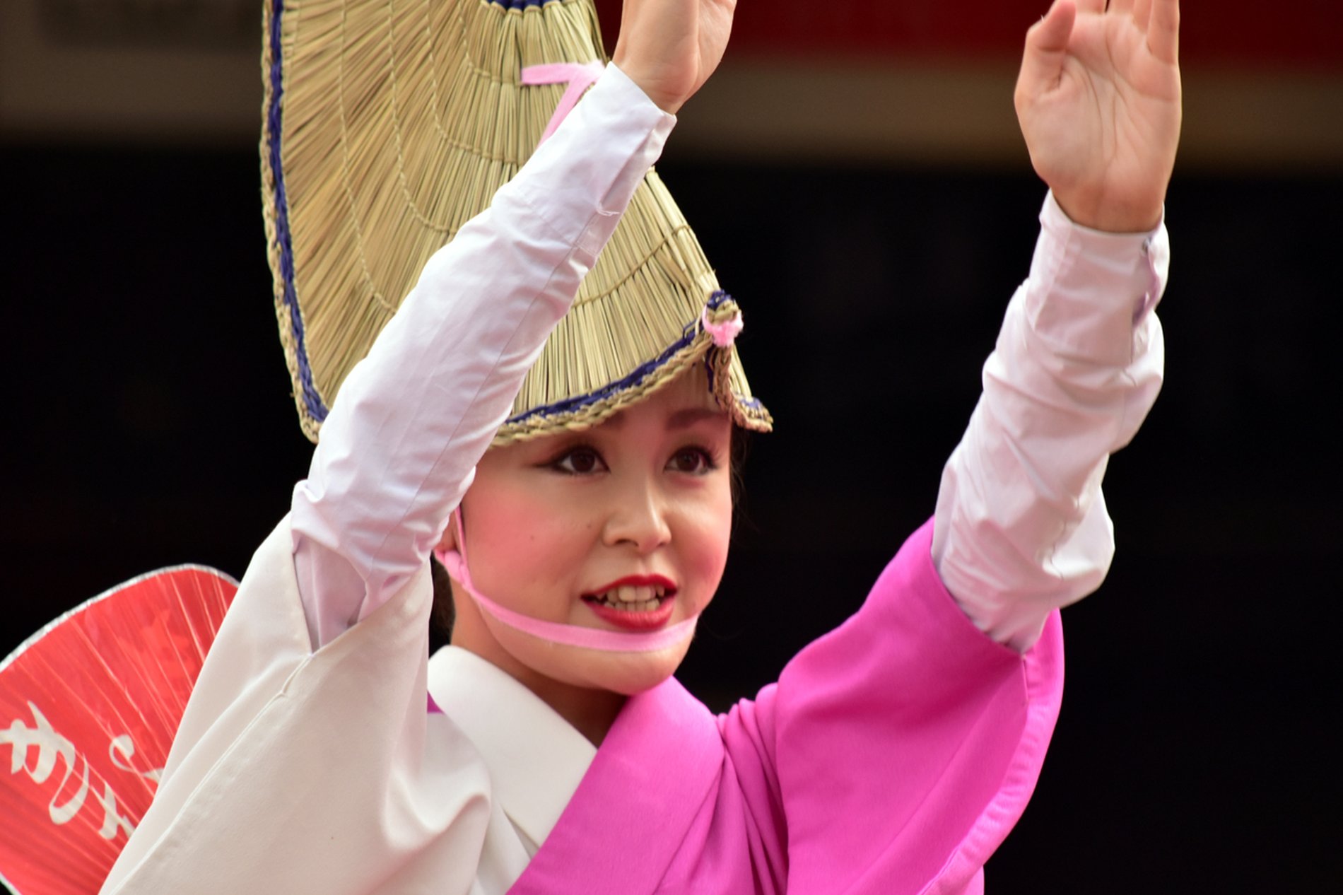 南越谷阿波踊りで、編笠をかぶりピンクの着物をまとった踊り子の女性が優雅に両手を上げて踊る姿