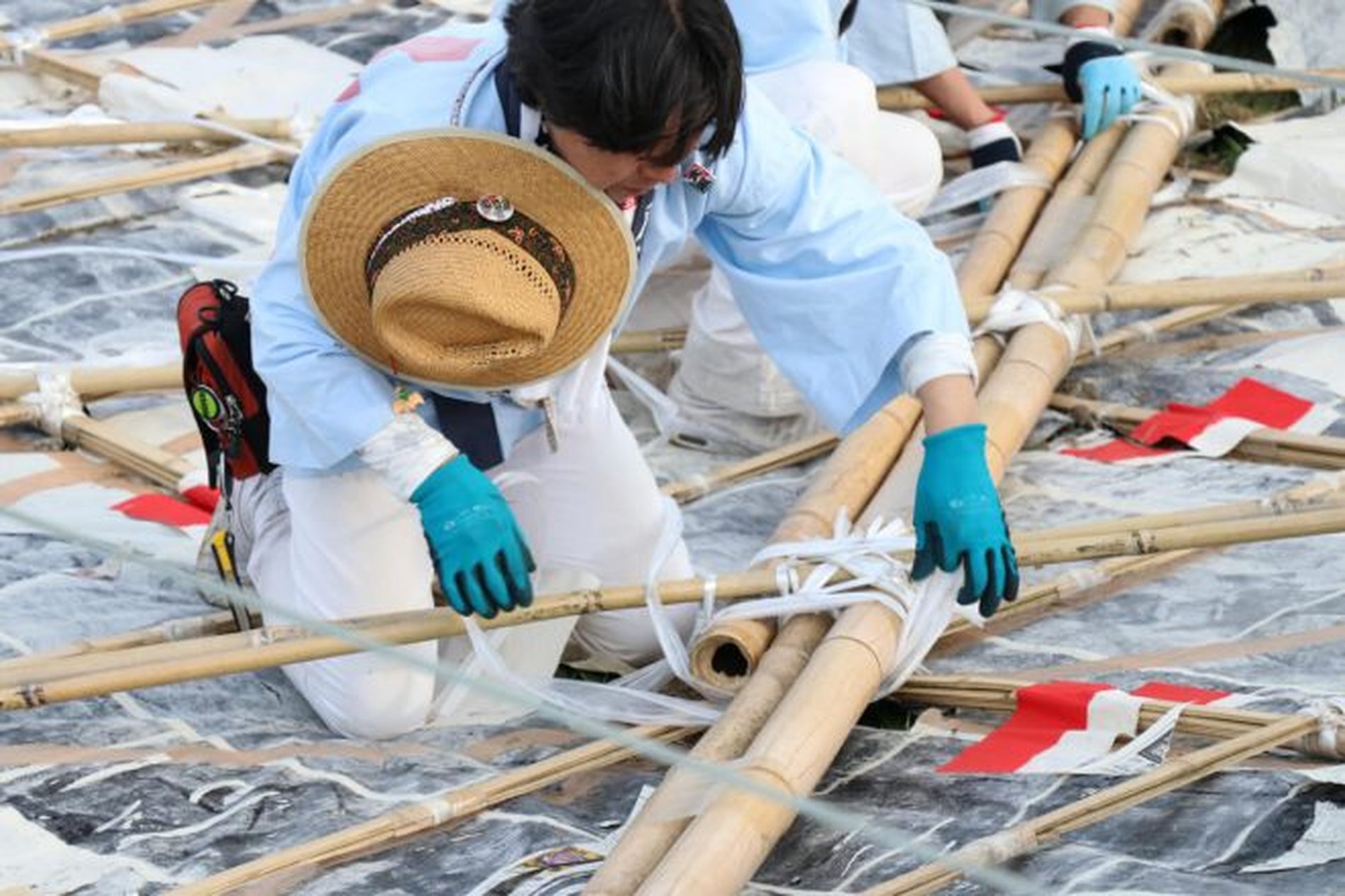 竹を組んだ骨組みに凧の布を結び付ける職人の手元の作業