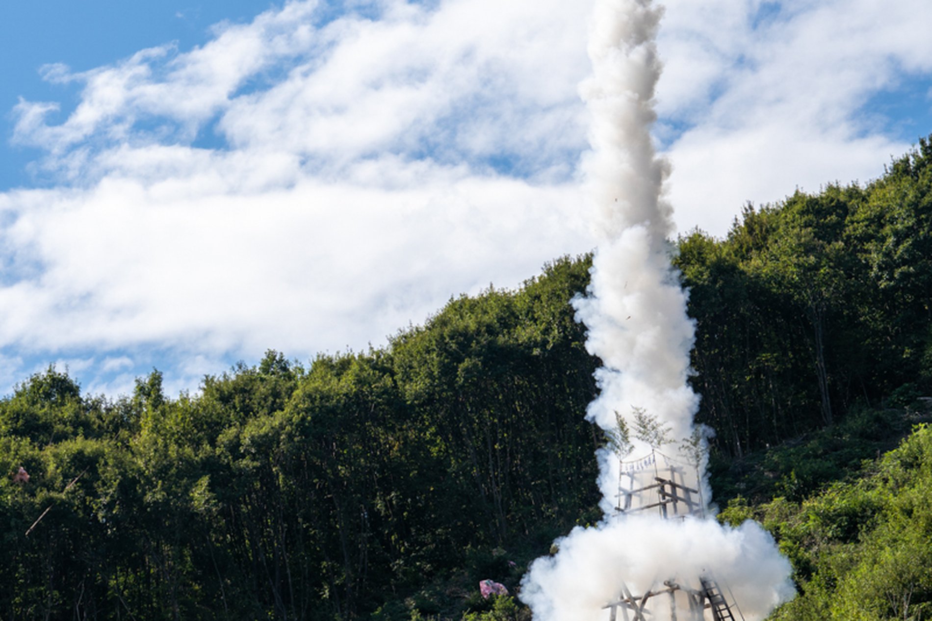 龍勢祭で山の斜面から手作りロケット『龍勢』が白煙をあげて打ち上がる様子