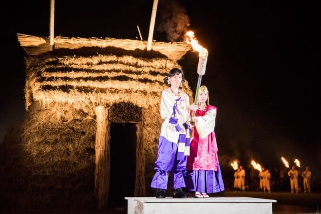 さきたま火祭りで儀式の舞台に立ち松明を掲げる二人の姿