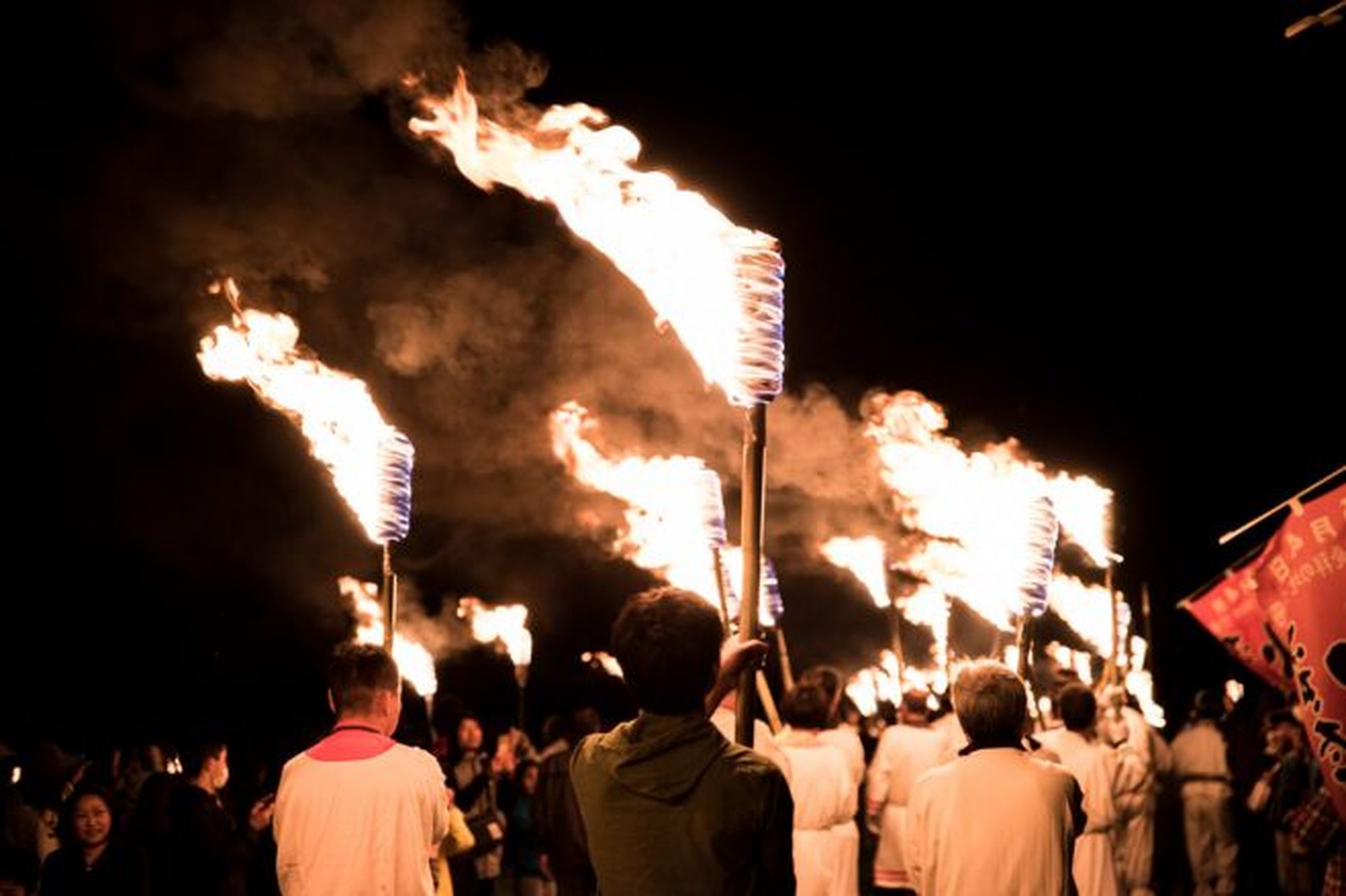 さきたま火祭りで松明を掲げ行進する参加者の様子