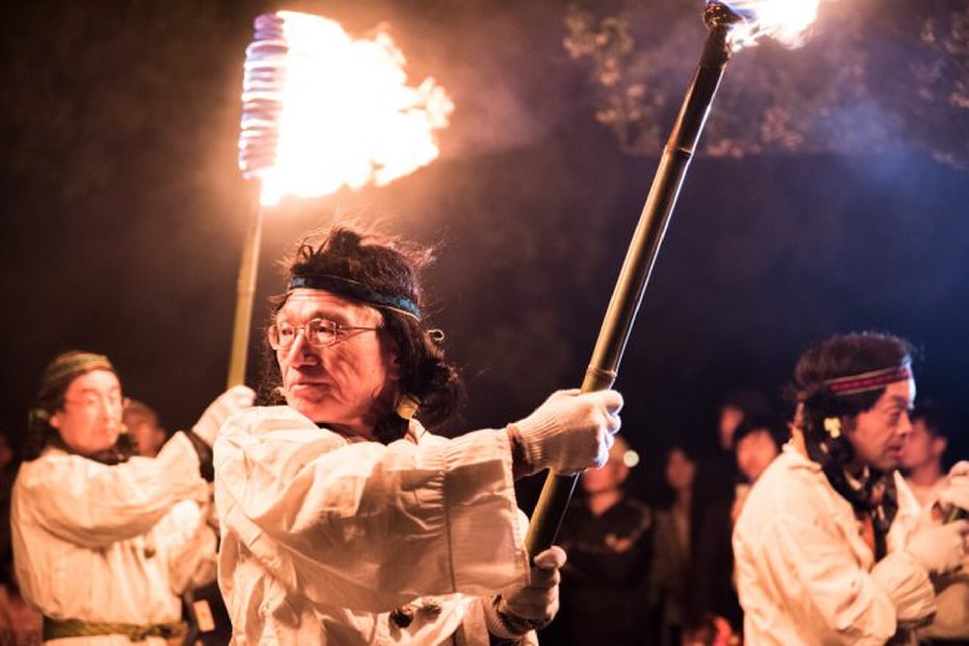 さきたま火祭りで松明を手に進む参加者の表情を捉えた場面