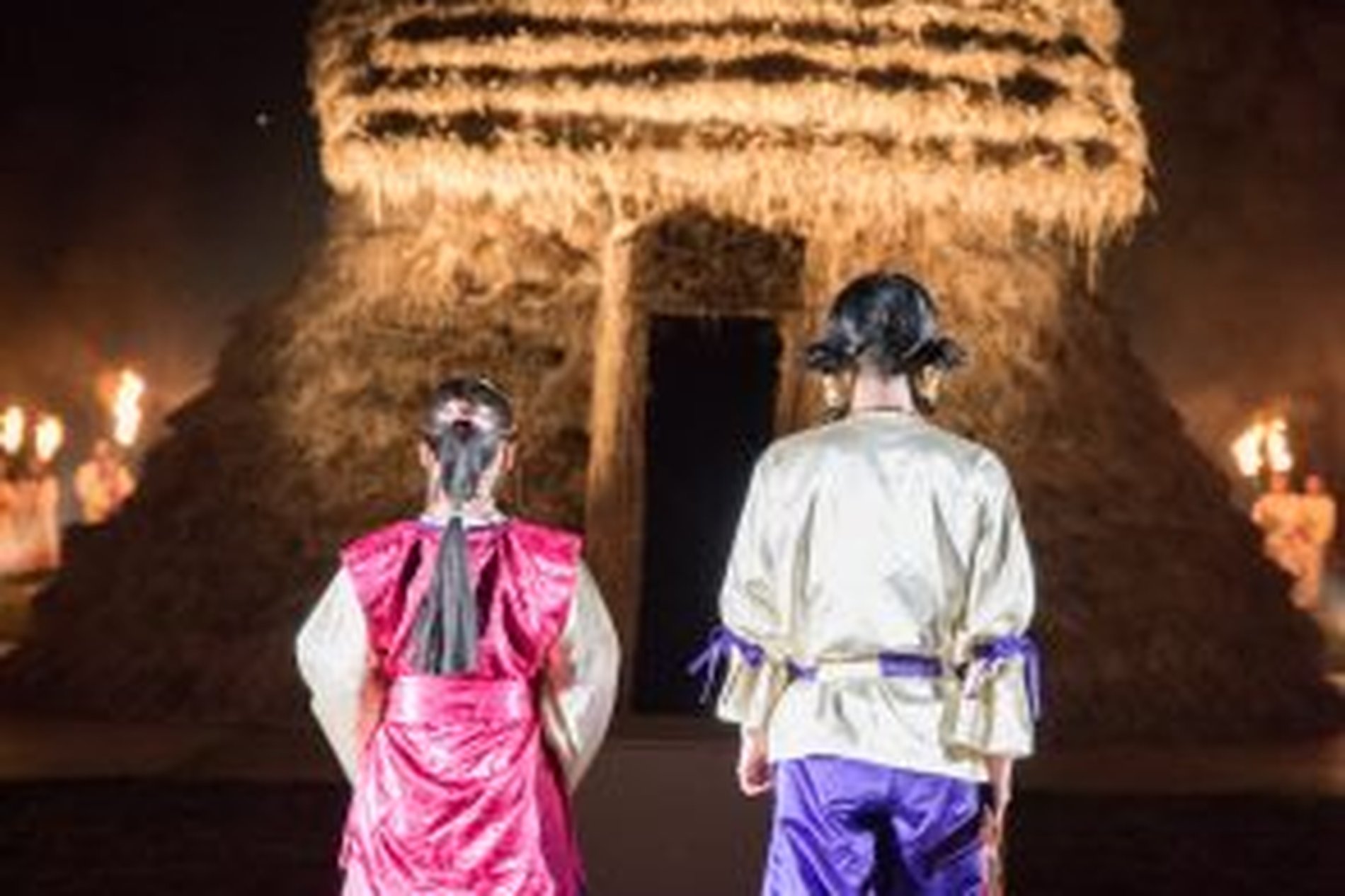 さきたま火祭りで藁殿を前に儀式衣装の二人が佇む後ろ姿