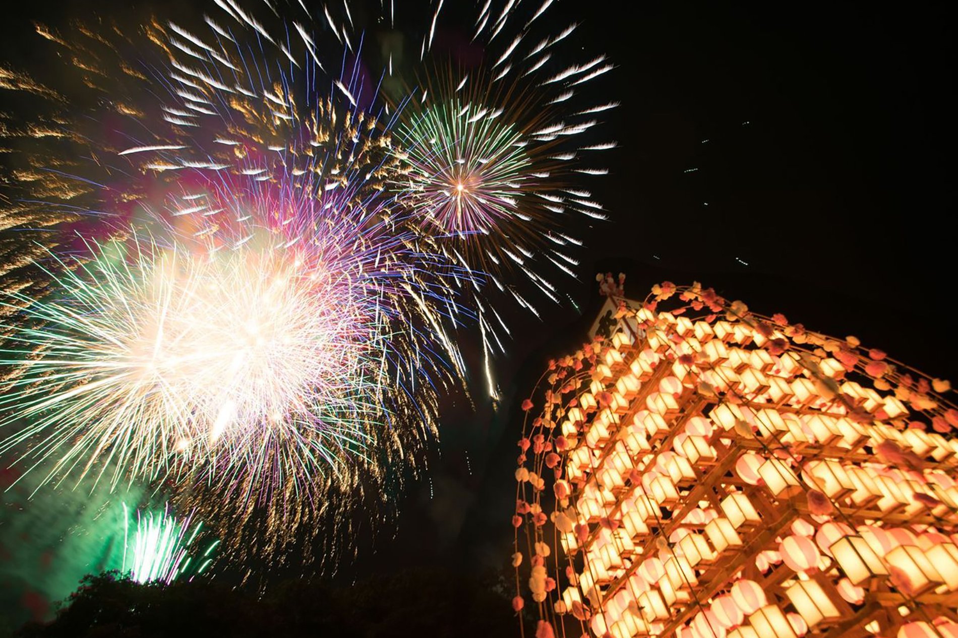 夜空に打ち上がる花火と、灯りがともった万灯が輝く寄居玉淀水天宮祭の夜景
